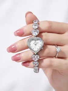Primo piano di un orologio gioiello d'argento a forma di cuore e anello di diamanti.