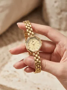 Macro detail of an elegant gold octagonal women quartz watch with link strap held in hand