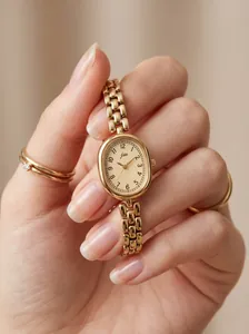 Close-up of a vintage JW gold oval watch with a chain strap held in hand