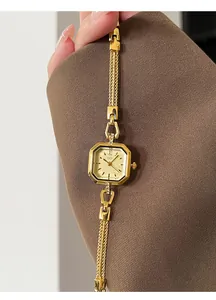Close-up of elegant square gold quartz watch with braided metal strap on wrist