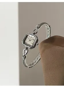 Close-up of elegant square silver ladies watch with metal mesh band and Roman dial.