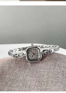 Detail view of elegant silver square quartz watch with decorative bracelet strap