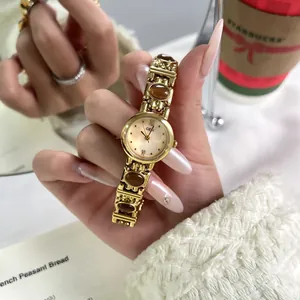 Detailed close-up of a vintage gold hand-cuff watch featuring tiger eye stone inserts.