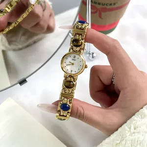 Detailed view of vintage GEDI gold bangle watch with tiger's eye and blue stone accents