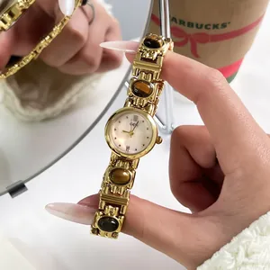 Close-up of vintage gold women's bracelet watch featuring brown tiger eye stones details