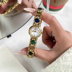 Detailed view of a vintage gold bangle watch featuring colorful stones and a pearl dial