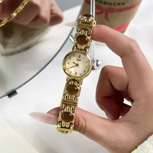 Close-up of GEDI vintage gold bangle watch with brown stones and a mother-of-pearl dial