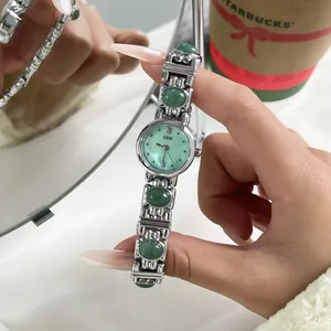 Detailed view of GEDI vintage silver bangle watch with green stones.