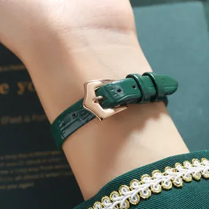 Close-up of a women's quartz watch with a green leather strap and gold buckle.