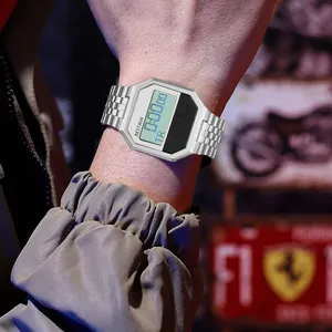 Detailansicht einer silbernen Digitaluhr am Handgelenk mit industriellem Hintergrund.