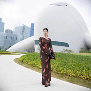 Elegant dark brown long-sleeved maxi dress with red floral print in modern urban setting