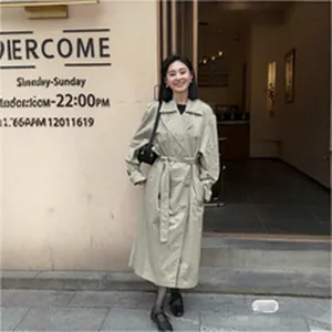 Elegant Asian model wearing a classic beige double-breasted long trench coat with belt