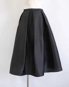Close-up detail of a high-waisted black pleated A-line skirt made of silk-wool blend