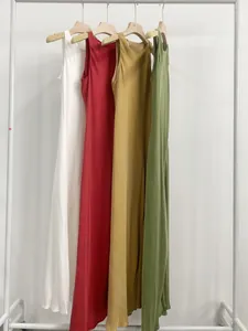 Eleganti abiti lunghi in cupro in quattro colori esposti su un appendiabiti bianco