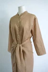 Detail van bruine lange ramie jurk met opstaande kraag en elegante overslag taille