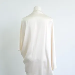 Elegante witte acetaat jurk met een gedrapeerde rug en een zijdeachtige glans.