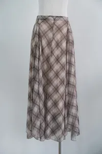 Close-up detail of the irregular hemline and flowy fabric on a brown plaid midi skirt
