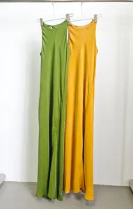 Dettaglio di eleganti abiti lunghi in cupro dalla vestibilità slim, colori verde e giallo.