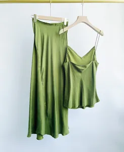 Elegant green Cupro silk set featuring a camisole and midi mermaid skirt on wooden hangers.