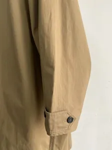 Vista de detalle del puño de la manga con botón ajustable en gabardina color caqui
