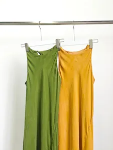 Eleganti abiti sottoveste in cupro verde e arancio appesi a un rack bianco minimal