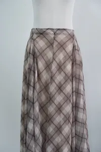 Close-up of brown plaid midi skirt fabric showing elegant drape and pattern details