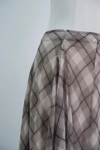 Close-up of elegant brown plaid fabric showing drape and fine texture on midi skirt