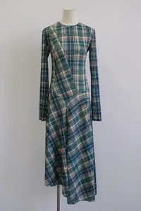 Detalle de vestido de manga larga con cuadros verdes y bajo asimétrico estilo diseñador.