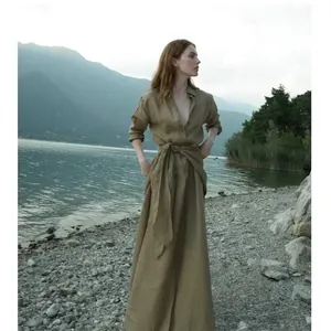 Professioneel model in een elegante linnen maxi-wikkeljurk in een serene meeromgeving