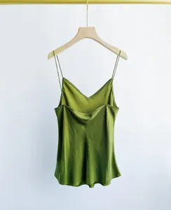 Detail view of a green sand-washed cupro silk camisole on a wooden hanger