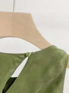 Dettaglio di un elegante abito in cupro verde con chiusura posteriore a bottone
