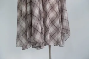 Detail view of a brown plaid midi skirt with an elegant airy irregular hem design