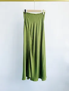 Elegant moss green cupro silk fishtail midi skirt hanging on a golden hanger