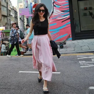 Lifestyle street style model wearing a pleated pink silk-wool blend A-line midi skirt