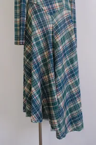 Detalle de primer plano de un vestido de diseñador de manga larga a cuadros verdes entallado.