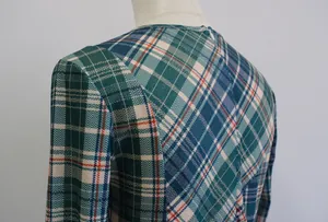 Primer plano del vestido de cuadros verde y azul que muestra el detalle del hombro y tela.