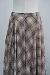 Detail view of brown plaid midi skirt featuring a back zipper and elegant draped fabric.