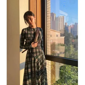 Elegante modelo asiática con un vestido de cuadros entallado y manga larga