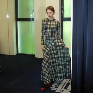 Vista completa de un vestido largo de diseño a cuadros verdes con mangas largas en una modelo