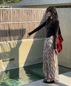 Close-up of a flowy brown plaid midi skirt with irregular hem in a garden setting