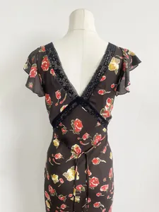 Detalle de cerca de un vestido de seda floral con encaje negro y volantes suaves.