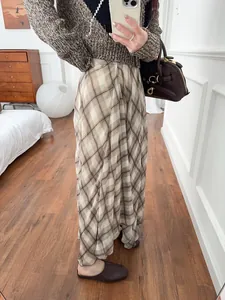 Full view of elegant brown plaid midi skirt with irregular hem and flowy drape.