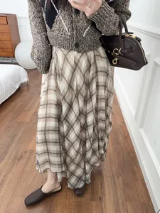 Detail view of an elegant brown plaid irregular midi skirt featuring fluid drape and soft texture