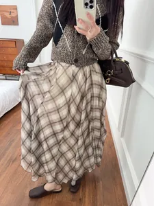 Detailed view of an elegant brown plaid irregular midi skirt with a flowy drape and hem