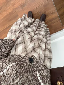 Close-up detail of a French style brown plaid midi skirt paired with a cozy knit cardigan