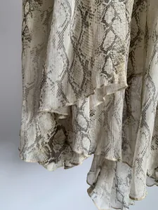 Close-up detail of flowing snake print chiffon fabric with an irregular layered hemline