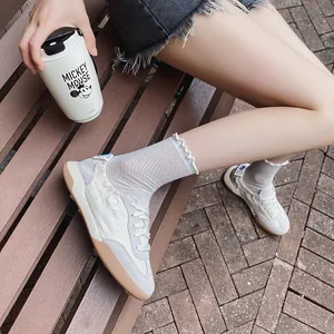 Breathable white German trainer sneakers for women styled on a wooden park bench