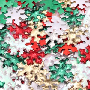 Detalle de lentejuelas festivas con forma de copo de nieve en varios colores y texturas metálicas.