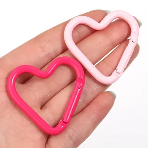 Vista ravvicinata di due moschettoni in alluminio rosa a forma di cuore tenuti in mano