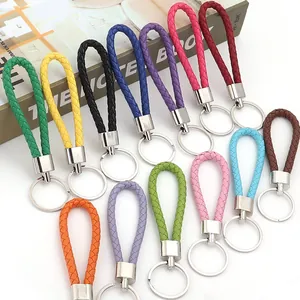 Variété de cordons en cuir tressé colorés avec porte-clés argentés sur fond blanc.